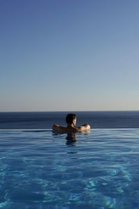 Man swimming in sea against clear sky
