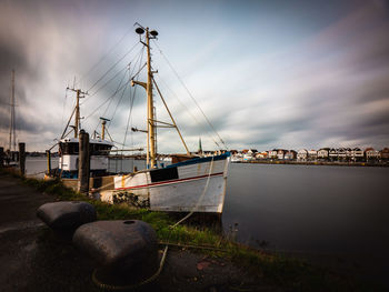 Sailboats moored in harbor against sky