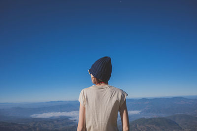 Rear view of man looking at mountain against clear blue sky