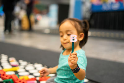 Cute girl holding stick with alphabet