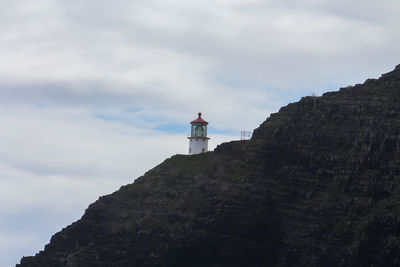 Low angle view of lighthouse by building against sky