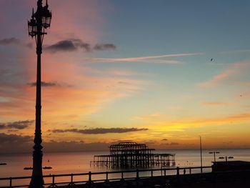 Silhouette built structure by sea against sky during sunset