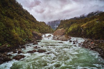 Scenic view of river flowing amidst mountains against sky