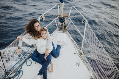 Smiling mother and daughter enjoying vacation on sailboat