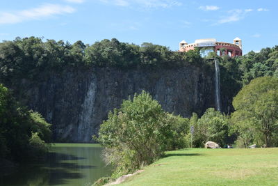 Lake by grassy field against rock formations in park during sunny day