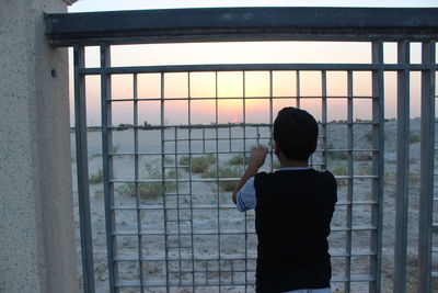 Rear view of boy standing against window