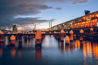 Illuminated bridge over river against sky at sunset