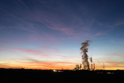 Smoke emitting from factory against sky during sunset