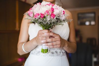 Midsection of bride holding flower bouquet