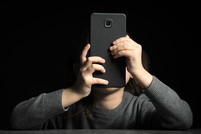 Midsection of man using mobile phone against black background