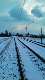 View of railway tracks against cloudy sky during winter