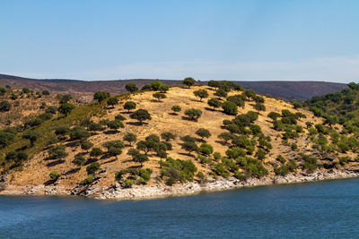 Scenic view of sea and mountains against clear blue sky