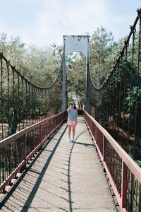 Full length of young woman standing on footbridge