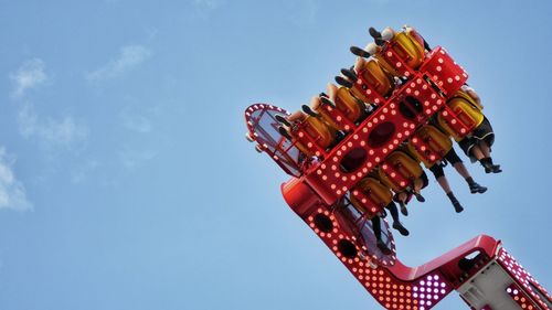 Low angle view of red amusement park ride against blue sky