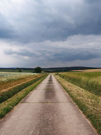 Road amidst field against sky