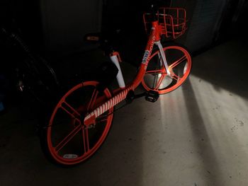 High angle view of bicycle wheel by illuminated wall at night