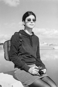 Young man sitting against sky