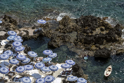 High angle view of sea, rocks and umbrellas