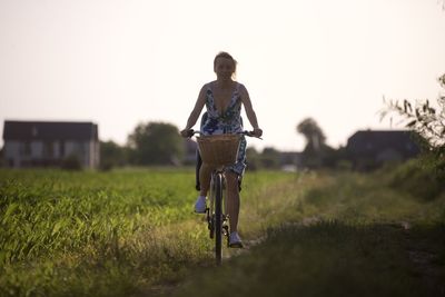 Rear view of man riding bicycle on field