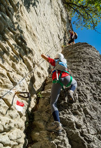 Low angle view of woman climbing on rock