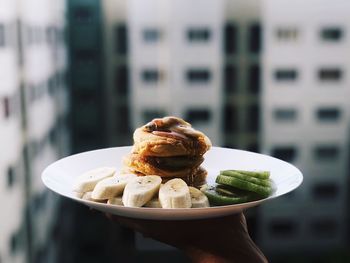 Cropped hand holding breakfast against window