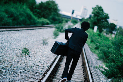 Rear view of man walking on railroad track