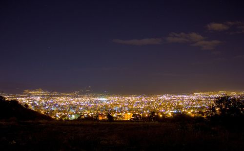 High angle view of illuminated cityscape against sky at night