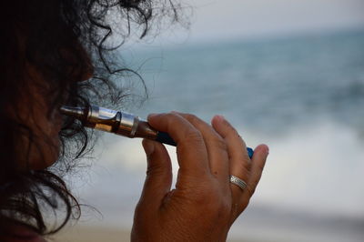 Close-up of woman smoking electronic cigarette at beach