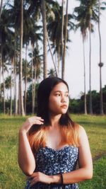 Portrait of young woman standing against trees