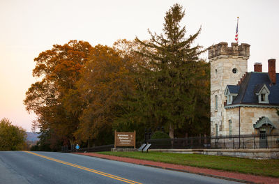 Road by trees and buildings against clear sky