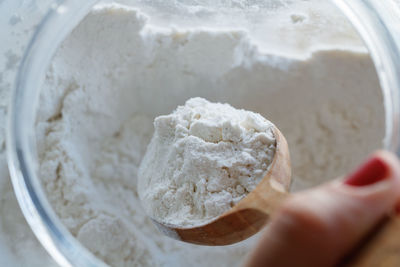 High angle view of woman hand removing flour from wooden spoon