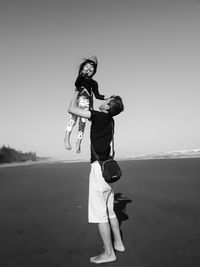 A father lifts up his daughter's body so as to make the child laugh out loud