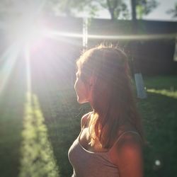 Woman with sunlight streaming against trees in park