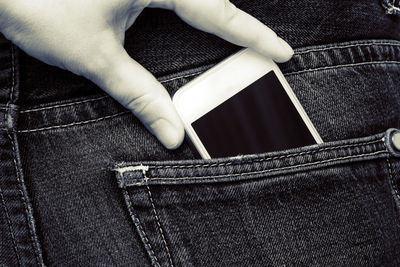 Cropped image of person keeping mobile phone in pocket