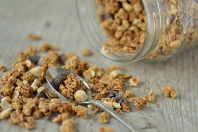 Close-up of granola in spoon by glass jar on table