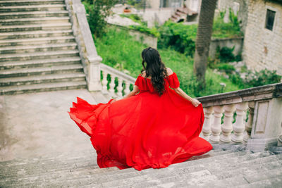 Rear view of woman in red dress moving down on steps