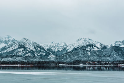 Scenic view of lake by snowcapped mountains against sky