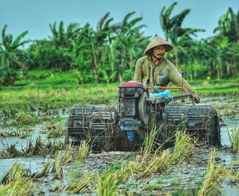 Farmer wearing asian style conical hat while working on agricultural field