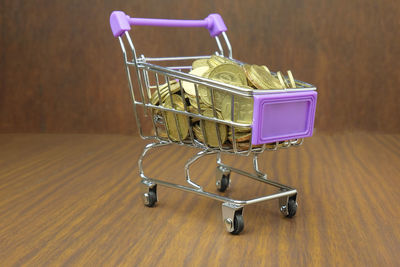 Close-up of coins in shopping cart on wooden table