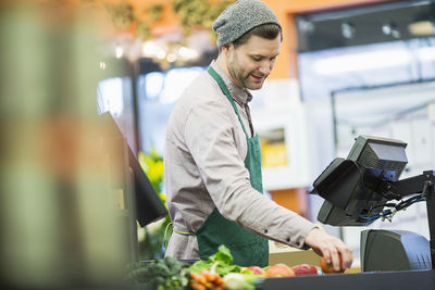 Man working while standing by counter at supermarket