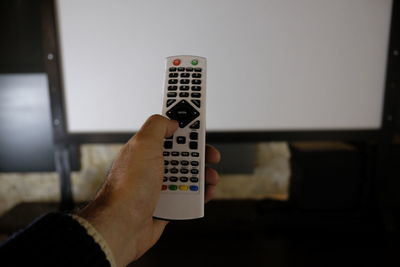 Cropped hand of man using remote at home