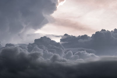 Low angle view of sunlight streaming through clouds