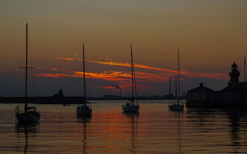 Silhouette sailboats in sea against sky during sunset