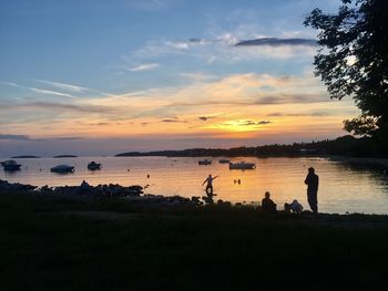 Silhouette people standing on beach against sky during sunset
