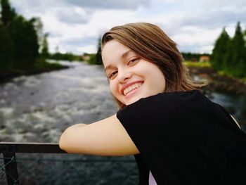 Portrait of smiling young woman leaning on railing