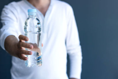 Midsection of man drinking water from bottle