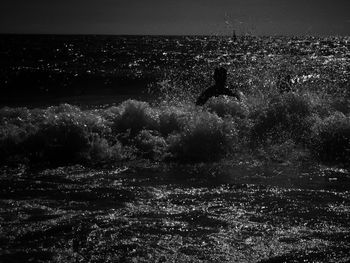 Silhouette man by sea against sky