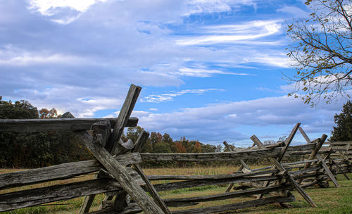 Old wooden fence on field against sky