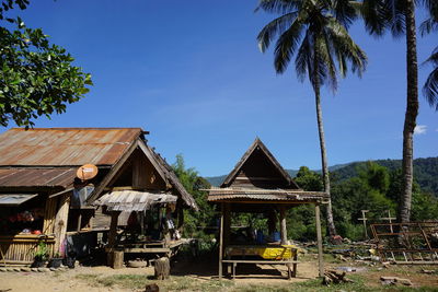 House by palm trees and houses against sky