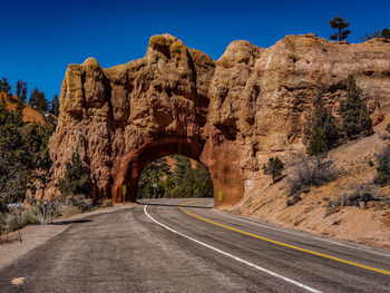 Road by rock formation against clear sky